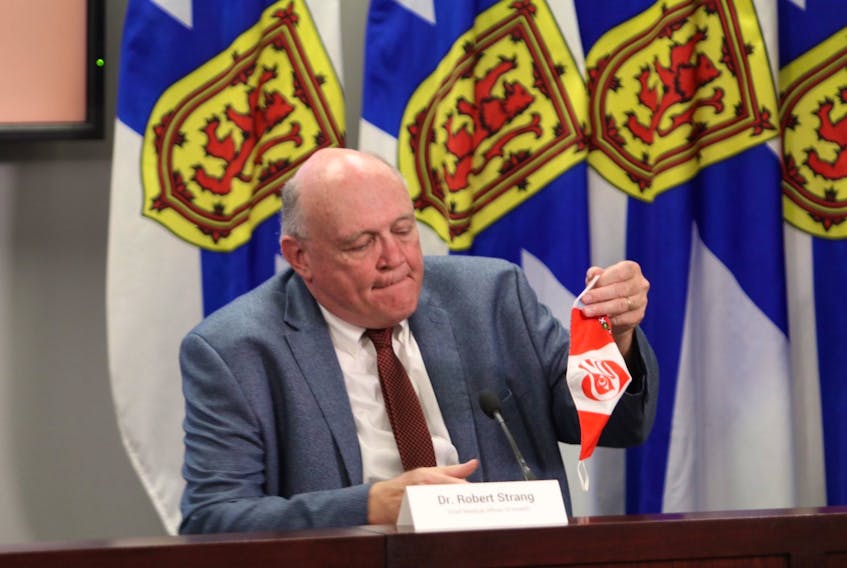 Dr. Robert Strang, Nova Scotia's chief medical officer of health, removes his non-medical mask before the start of a news briefing in Halifax on Friday, Aug. 14, 2020. - Eric Wynne