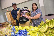 Rev. David Hockley, an assistant pastor at Yarmouth Wesleyan Church, and church volunteer Kathy Murphy hold a box of backpacks that will soon be filled with food as a part of a weekly program to help families in need. TINA COMEAU PHOTO
