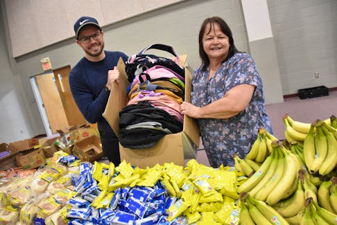 Rev. David Hockley, an assistant pastor at Yarmouth Wesleyan Church, and church volunteer Kathy Murphy hold a box of backpacks that will soon be filled with food as a part of a weekly program to help families in need. TINA COMEAU PHOTO