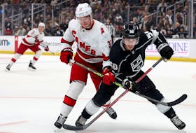 Los Angeles Kings' Sean Durzi (right) and Carolina Hurricanes' Andrei Svechnikov get tangled up as they skate after the puck at Crypto.com Arena on Dec. 3, 2022 in Los Angeles.