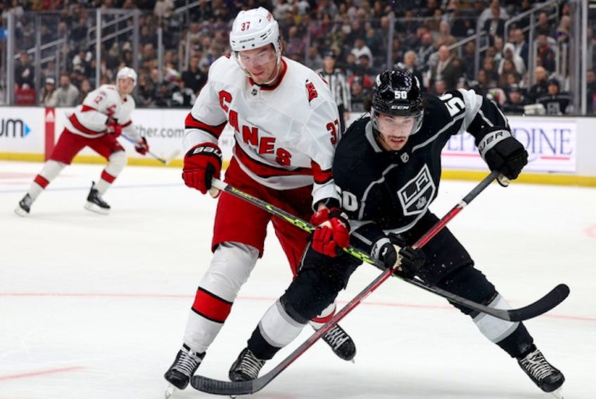 Los Angeles Kings' Sean Durzi (right) and Carolina Hurricanes' Andrei Svechnikov get tangled up as they skate after the puck at Crypto.com Arena on Dec. 3, 2022 in Los Angeles.