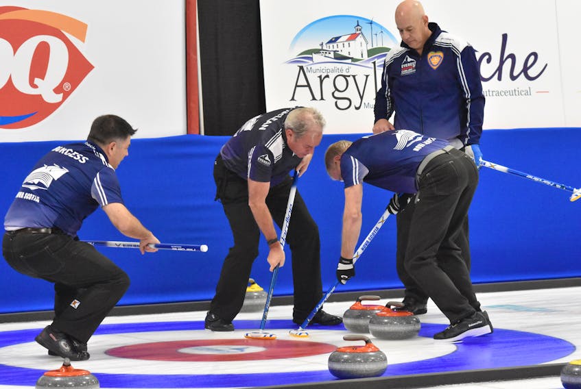 Nova Scotia skip Glen MacLeod, right looks on as Stuart MacLean and Peter Neily sweep a shot by Craig Burgess in Championship Pool play against New Brunswick on Thursday afternoon at the Mariners Centre in Yarmouth. MacLeod won the game 7-5. 