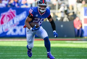 New York Giants running back Saquon Barkley runs with the ball against the Washington Commanders during the first half at MetLife Stadium.  