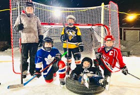 Young skaters gather at the Freake family backyard rink in Deer Lake in 2022: Ella Piccott (standing), Liam Curlew (Toronto jersey), Ryan Piccott (Pittsburg jersey), Joel Freake (Montreal jersey)  and Elliott Freake in tire. CONTRIBUTED