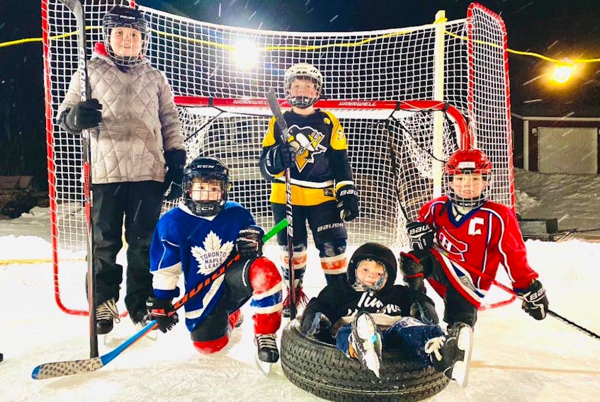 Young skaters gather at the Freake family backyard rink in Deer Lake in 2022: Ella Piccott (standing), Liam Curlew (Toronto jersey), Ryan Piccott (Pittsburg jersey), Joel Freake (Montreal jersey)  and Elliott Freake in tire. CONTRIBUTED