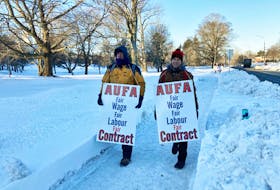 Two pickets walk the line in front of Acadia University in Wolfville early Tuesday morning, Feb. 1, 2022, after faculty union members went on strike after rejecting a contract offer that came from the university late Monday.
