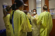  Nurses get ready before going in to assist a COVID-19 patient on the intensive care unit at Peter Lougheed in Calgary on Nov. 14, 2020.