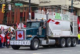 A flag-bedecked truck drives along Burrard Street amid anti-vaccination policy protests in downtown Vancouver last Saturday.