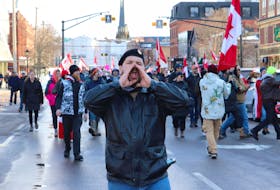Protestors on foot begin marching on Great George Street after a slow roll through Charlottetown while police block off roads from oncoming traffic on Feb. 12.