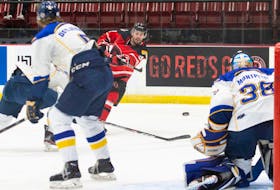 UNB Reds rookie forward Austen Keating fires a shot on Moncton Aigles Bleus goalie Etienne Montpetit during Atlantic university hockey action Saturday night in Fredericton. It was the first AUS men's hockey game played in over two months. - JAMES WEST / UNB ATHLETICS