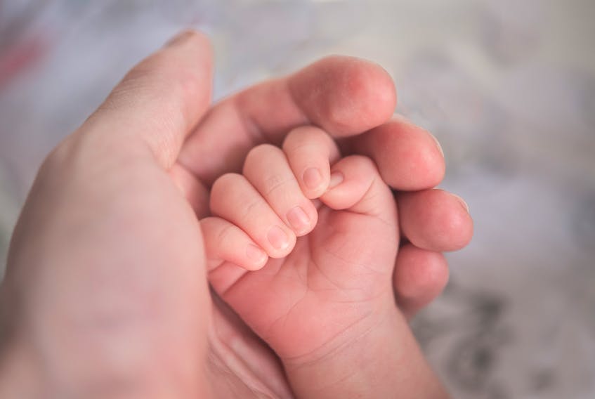 A mother holding her baby's hand. Courtesy of Unsplash Photos.