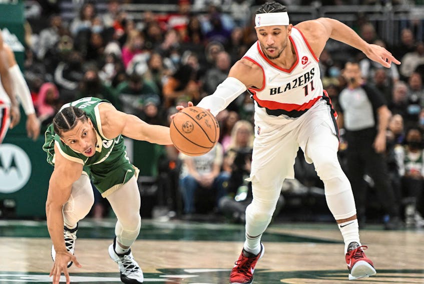Milwaukee Bucks guard Lindell Wigginton (28) and Portland Trail Blazers guard Josh Hart (11) reach for a loose ball in the third quarter of a game at Fiserv Forum in Milwaukee, Wis. on Monday, Feb. 14, 2022.