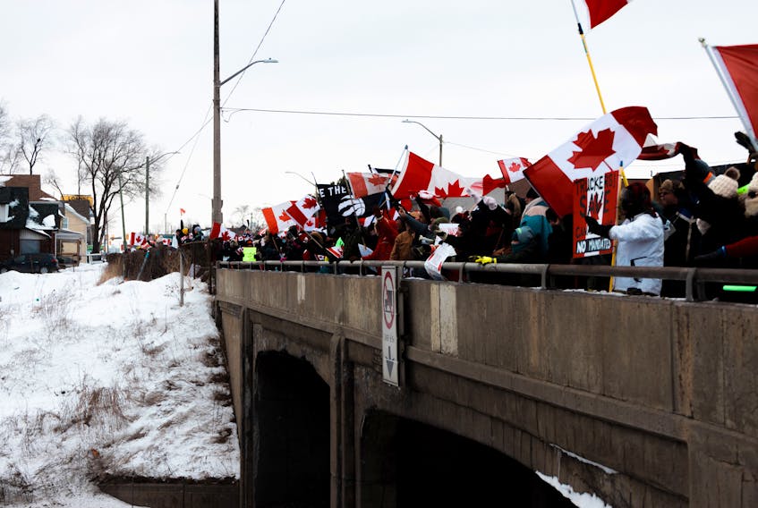People wave Canadian flags in support of truckers taking part in anti-mandate protests in Ontario. Dillon Kydd • Unsplash 