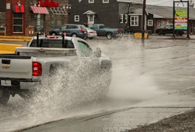 Cars crash through floodwaters along Kings Road in Sydney River on Friday morning. JESSICA SMITH/CAPE BRETON POST
