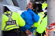 A protester yells “hold the line” while being taken away under arrest in Ottawa on Friday, February 18, 2022.