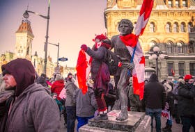 A protester stands on the Terry Fox statue in Ottawa during the Jan. 29 protest against vaccine mandates for cross-border truckers. 