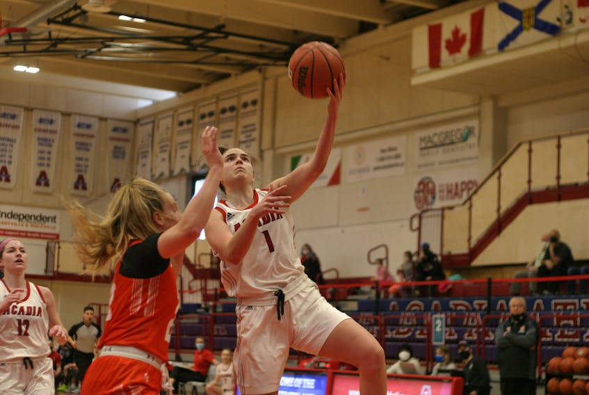 Acadia Axewomen wing Sandy Saunders looks to finish with her left hand while being defended by Cape Breton Capers forward Catherine Lallemant-Capocci Feb. 20 at Stu Aberdeen Court in Wolfville.