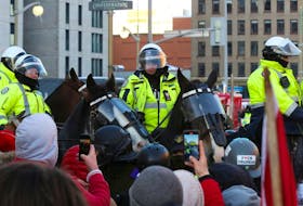 Demonstrators stand in front of Canadian police officers riding horses, as truckers and supporters continue to protest coronavirus disease (COVID-19) vaccine mandates, in Ottawa, Ontario, Canada, February 18, 2022.
