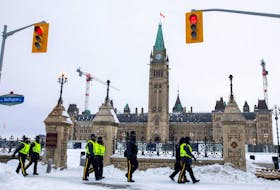 Police officers walk along Wellington Street in Ottawa on Feb. 20 as Canadian police worked to evict the last of the trucks and supporters occupying the downtown core, three weeks after a protest against COVID-19 vaccine mandates began. Carlos Osorio/Postmedia 