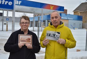 Cheryl Cudmore, left, and her brother, Tom Cudmore, hold up historic photos of their father’s gas station on the corner of Fitzroy and Great George streets in Charlottetown.