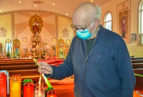 Father Roman Dusanowskyj, priest at the Holy Ghost Ukrainian Catholic Church, lights a candle in the church for those in Ukraine. JESSICA SMITH/CAPE BRETON POST