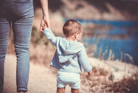 Stock photo of parent walking with toddler. - Photo by Guillaume de Germain on Unsplash