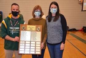 Three Oaks Senior High School athletic director Joel Arsenault, left, and Lynn Turtle, centre, display the plaque for the P.E.I. School Athletic Association’s newly renamed Garth Turtle Merit Award. Lynn and Kristen Turtle, right, participated in a ceremony honouring the contributions of their late husband and father to school sports in P.E.I. on Feb. 23 before the home opener of the Three Oaks Axewomen senior AAA basketball team, which Garth coached for many years.