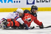 Canadian defenceman Liam Hickey fends off Declan Farmer (16) of the United States during the goal-medal final of the IPC world men's para hockey championship in Ostrava, Czech Republic.  —  Hockey Canada