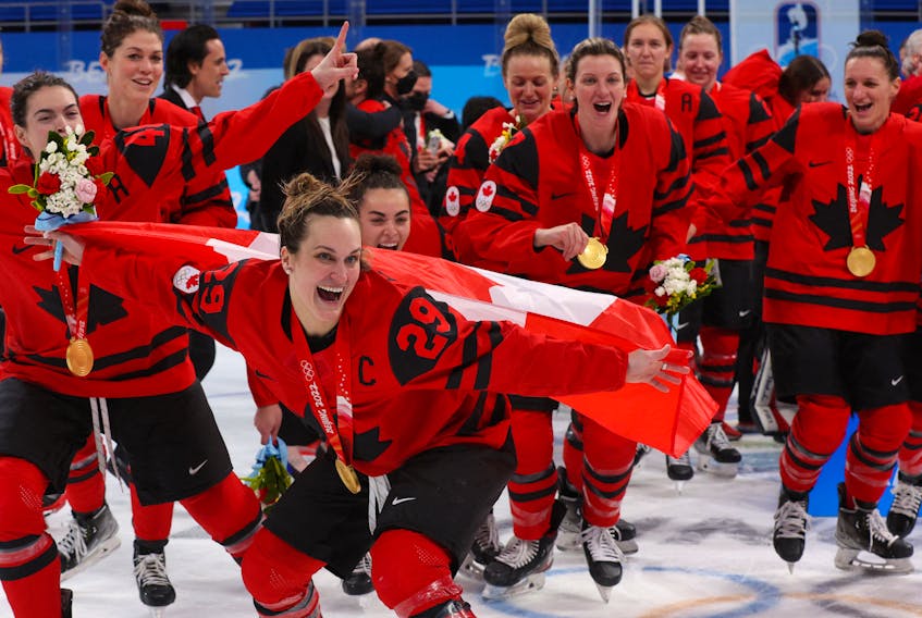 Canada’s Marie-Philip Poulin, front, Blayre Turnbull, left, and Jill Saulnier, right, celebrate with their gold medals after defeating the United States 3-2 in the women’s hockey championship game at the Beijing Olympics on Feb. 17.  Brian Snyder • Reuters