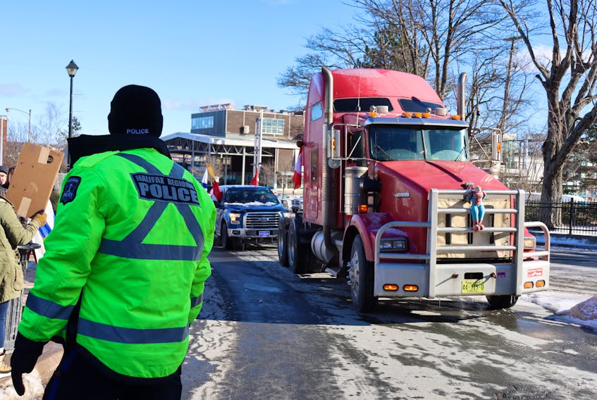 /A Halifax Regional Police officer directs traffic as a transport truck leads an anti-mandate convoy through downtown Halifax on Sunday, Feb. 6, 2022.