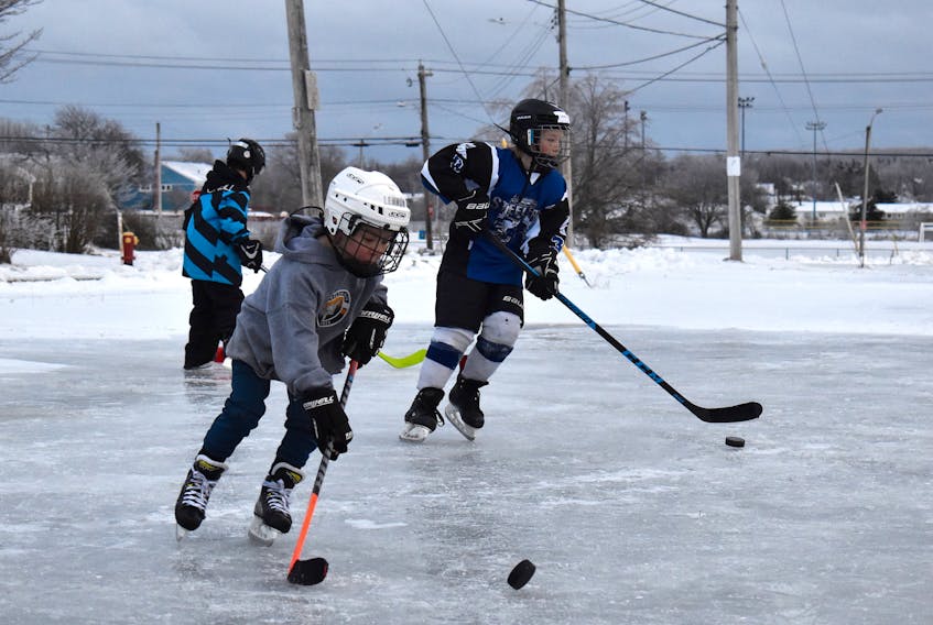 Lennon MacPherson, left, and Joyce Leviten-Reid joined four fellow hockey players in practicing their stickhandling on a homemade rink in the parking lot of the former Southend Community Centre on Hillview Street in Sydney on Monday. The rink was made by Robert Coates and his sons Neo and Easton Coates, who were also on the ice. The family put water in a five-gallon plastic garbage can and pulled it up the hill by sled. Robert Coates told the Cape Breton Post the family made 30-to-40 trips up to the parking lot with the water. The ice was smooth with very little bumps, making for ideal skating conditions. Unfortunately, Coates anticipated the rink being washed away Tuesday and Wednesday with the latest storm rolling through the area. JEREMY FRASER/CAPE BRETON POST.