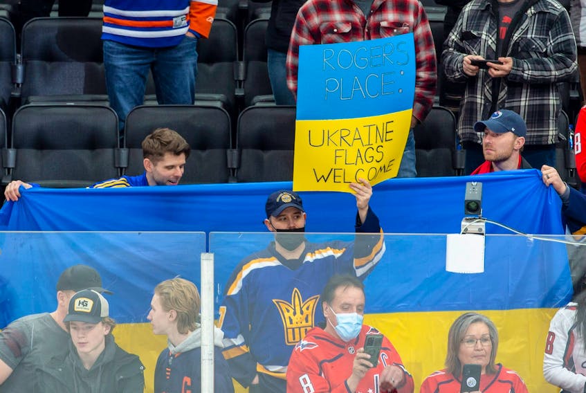 Fans hold a Ukrainian flag in support of the Ukrainian people before the Edmonton Oilers play the Washington Capitals on Wednesday, March 9, 2022 in Edmonton.     