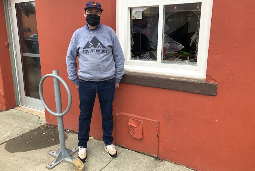 James Walsh, co-owner of Doktor Luke's coffee shop in downtown Sydney discovered Saturday morning that the take-out window of his shop was smashed overnight. The large rock at his feet was found at the scene. ARDELLE REYNOLDS/CAPE BRETON POST