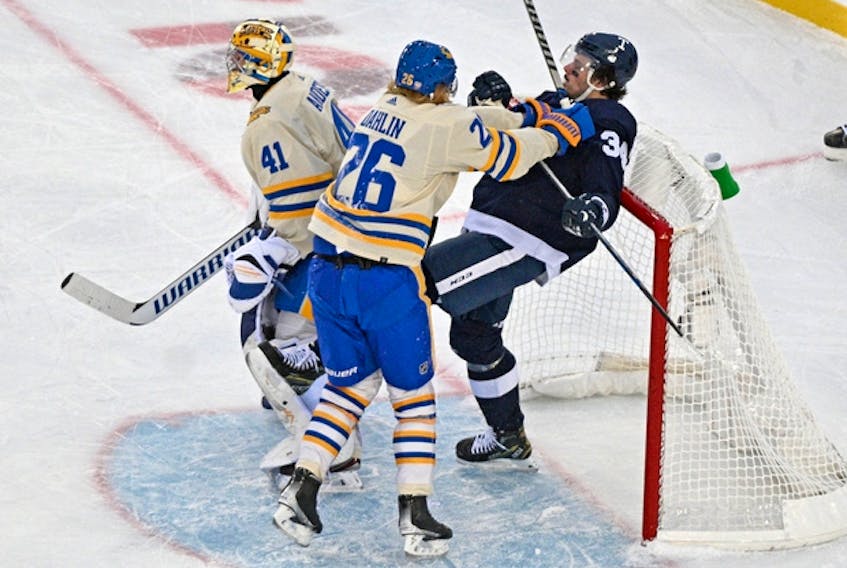Buffalo Sabres defenceman Rasmus Dahlin (left) shoves Toronto Maple Leafs sniper Auston Matthews into the net behind goalie Craig Anderson during the Heritage Classic on Sunday at Tim Hortons Field.