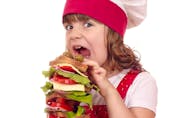 hungry little girl cook eat large sandwich