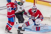 A puck sails through the crease of Montreal Canadiens goaltender Cayden Primeau (30) with teammate defenseman Chris Wideman (20) and Arizona Coyotes right wing Christian Fischer (36) at the doorstep during 3rd period NHL action at the Bell Centre in Montreal on Tuesday, March 15, 2022.