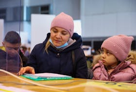 A woman with children waits in an immigration office in Brussels on March 14 after fleeing from Ukraine to Belgium, following Russia's invasion of Ukraine. In Quebec, refugee children — even those with a knowledge of English — will have to attend French schools, says the CAQ government.