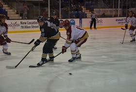 Charlottetown Islanders forward and team captain Brett Budgell focuses on redirecting the puck while the Acadie-Bathurst Titan’s Noah Ryan looks to break up the play. during a QMJHL game in Charlottetown earlier this season. Budgell enters the Islanders’ home game against Moncton on March 17 on a 10-game point streak.