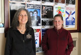 Executive director Farida Gabbani and business and booking manager Lori McCallum stand in front of the board of posters advertising upcoming events as people walk into the Marigold Cultural Centre. 