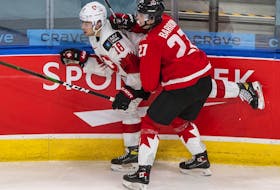 Canada's Justin Barron checks Switzerland's Inaki Baragano during first period of world junior championship game in Edmonton on Dec. 29, 2020.