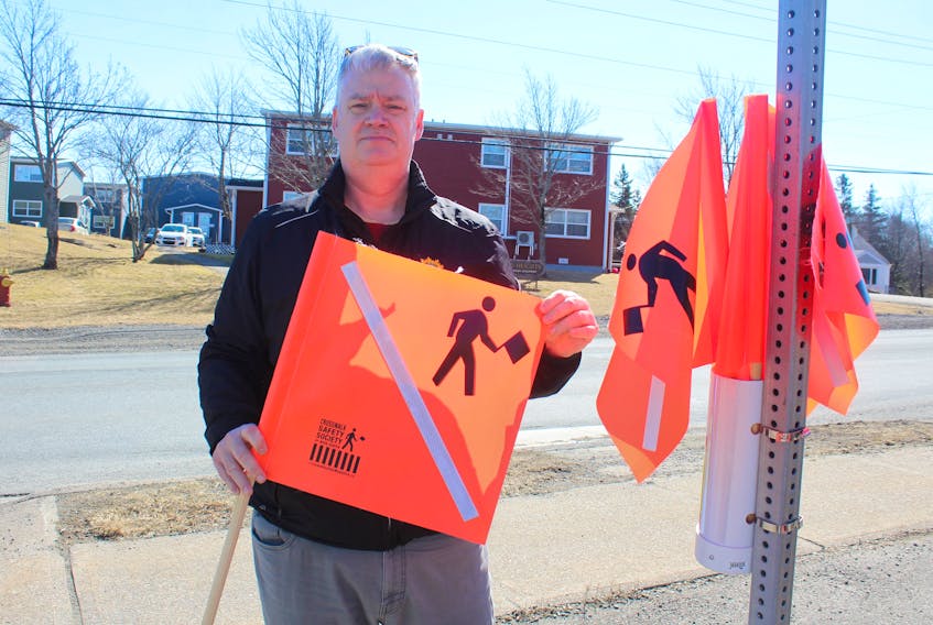 CBRM Coun. Steve Gillespie displays one of a series of crosswalk flags he purchased and has set at different crosswalk locations throughout his district, including this one at Alexandra Street near the Kenwood Drive roundabout and Highway 125. IAN NATHANSON/CAPE BRETON POST