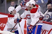 Montreal Canadiens' Nick Suzuki, centre, celebrates his goal against the Winnipeg Jets with Cole Caufield  and Josh Anderson during first period in Winnipeg on March 1, 2022.