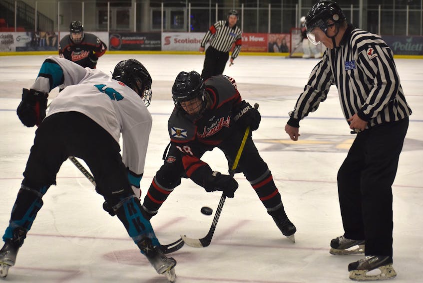 Jacob MacDonald of the New Waterford Sharks, left, and Stan Paul of the Cape Breton County Islanders, middle, battle to win the faceoff as linesman Harold MacNeil drops the puck during Cape Breton Hockey League under-18 'AA' Cape Breton Cup championship action at the Membertou Sport and Wellness Centre on Tuesday. Cape Breton County won the game 2-1 to claim the title. JEREMY FRASER/CAPE BRETON POST.