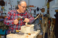 Frank Kim uses a wooden mallet and chisel to shape a walking stick. Chris Connors/Cape Breton Post
