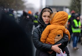 A woman carries a child after fleeing from Russia's invasion of Ukraine, at the border crossing in Siret, Romania, March 2, 2022.