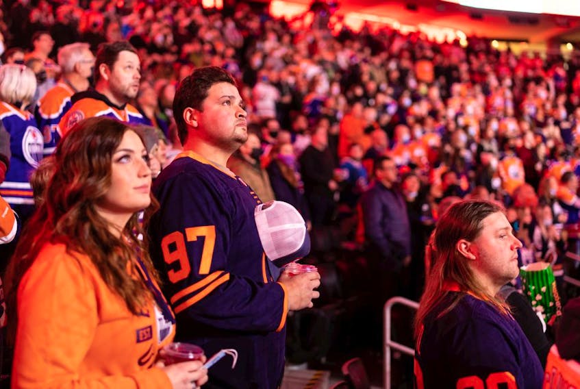 Hockey fans sing the national anthem as the Edmonton Oilers take on the Columbus Blue Jackets during a NHL game at Rogers Place in Edmonton on Dec. 16, 2021.