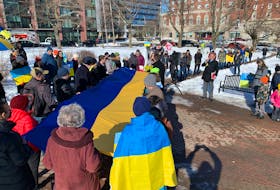 Participants at a rally for Ukraine with a Ukrainian flag help form a human chain on Saturday, March 5, 2022, in Halifax.