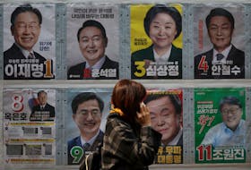 A woman walks past posters of candidates for the upcoming presidential election in Seoul, South Korea on Monday. REUTERS/Kim Hong-Ji