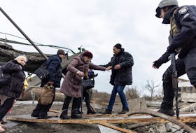 Ukrainians cross a destroyed bridge as they evacuate from the town of Irpin after days of heavy shelling on the only escape route used by locals as Russian troops advance towards the capital, in Irpin, near Kyiv on March 7. REUTERS/Carlos Barria