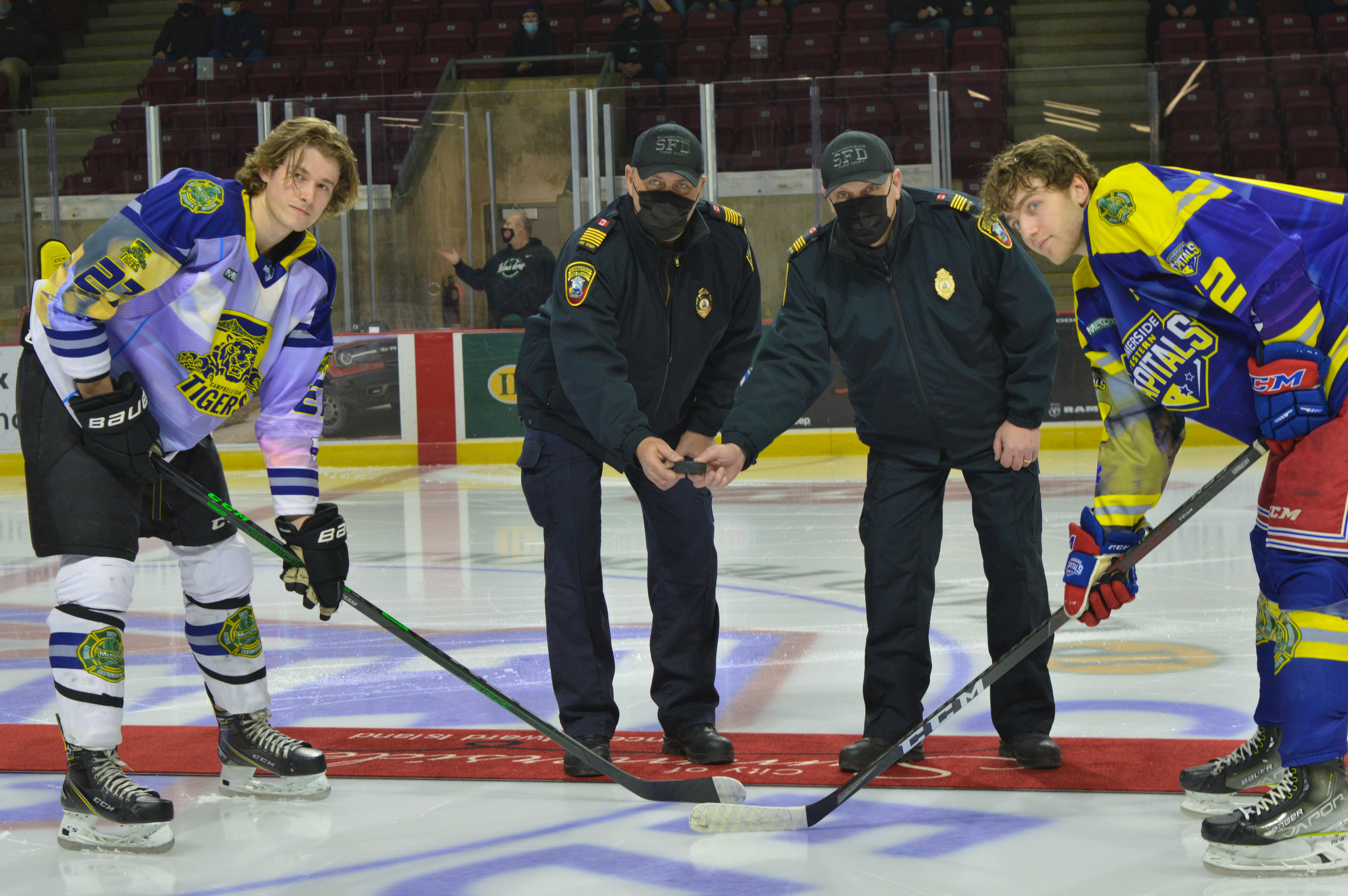 Summerside fire Chief Ron Enman, left, and deputy chief Kenny Blanchard drop the puck for the ceremonial faceoff between Summerside Western Capitals foward Colby MacArthur and Campbellton Tigers forward Jordan Briere on Saturday, March 5. The Capitals and Tigers honoured first responders in the region during a pre-game ceremony as part of a league-wide initiative.

